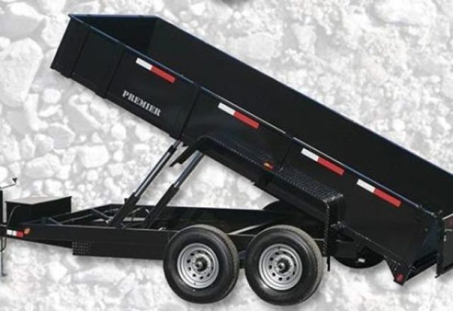 black tandem axle dump trailer that is elevated to dump with attachments